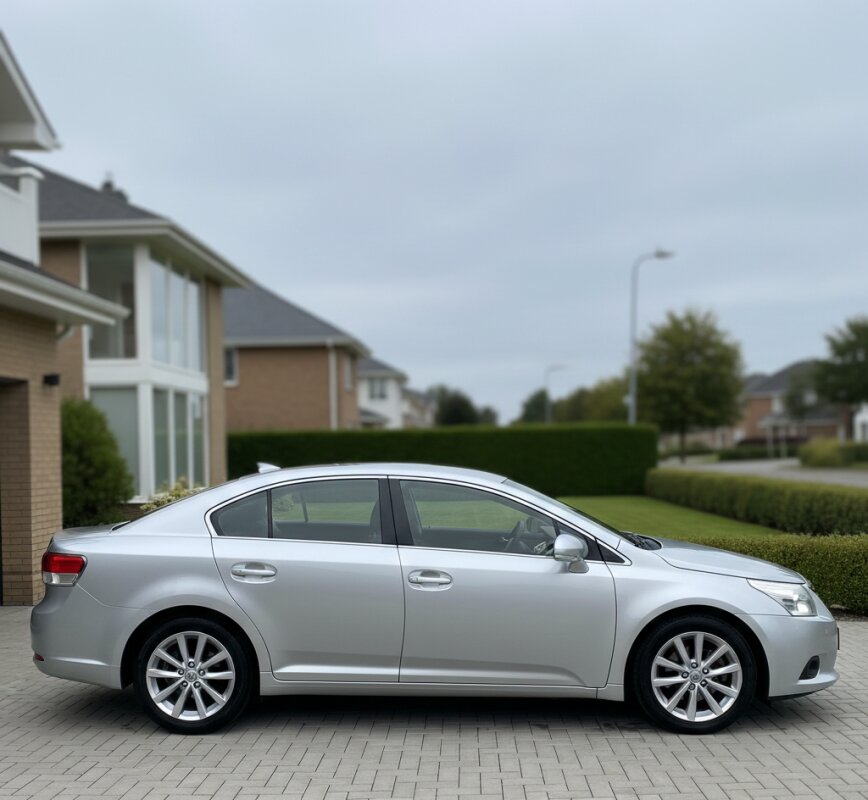 Srebrna Toyota Avensis T27 sedan w miejskiej scenerii.