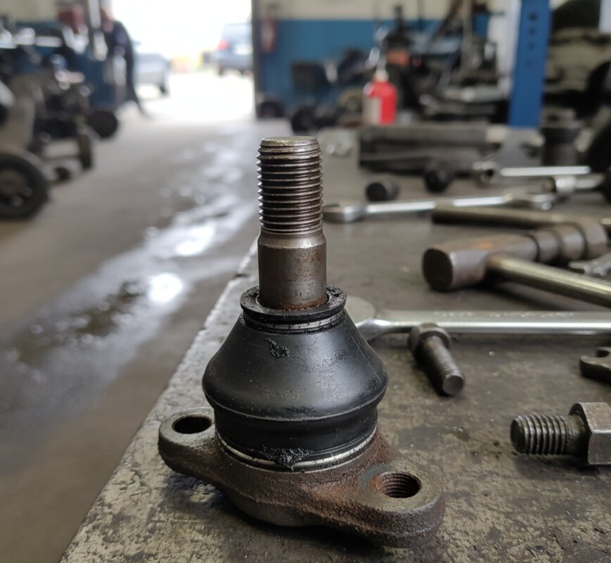 Zużyty sworzeń wahacza z pękniętą osłoną gumową.